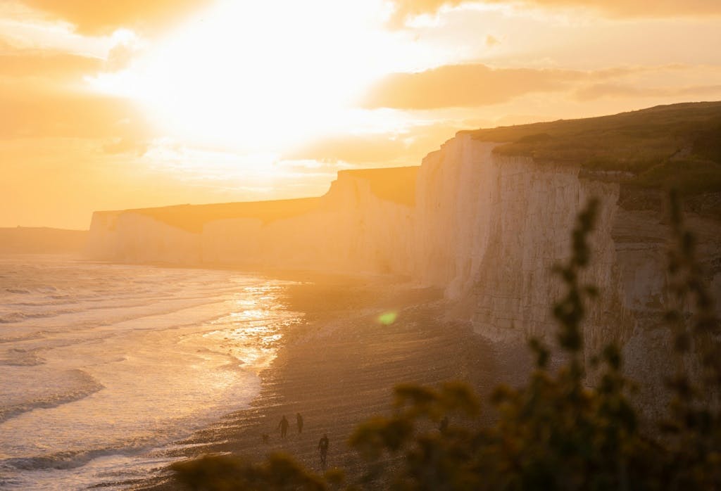 View of the cliffs and sea in Eastbourne, in the UK, with the sun blazing above them against a yellow sky