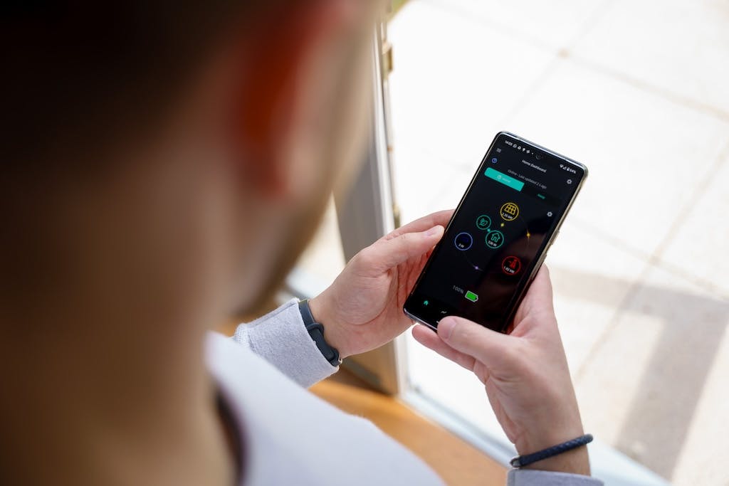 A man using GivEnergy's solar panel monitoring app on his phone, viewed from behind his head