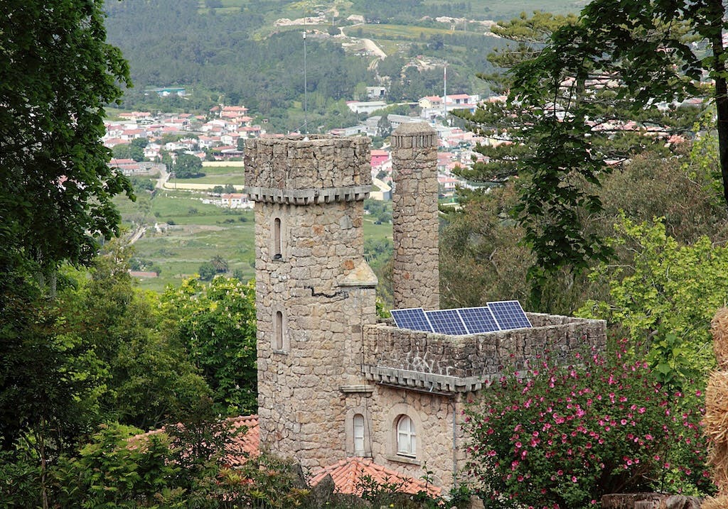 A small solar panel array on a small castle, lots of green countryside in the background