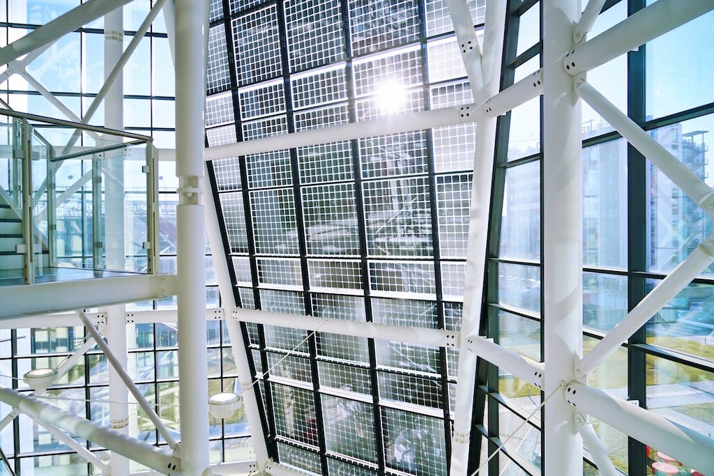 A semi-transparent solar panel array on the interior side of an office building, the sun shining through windows onto it