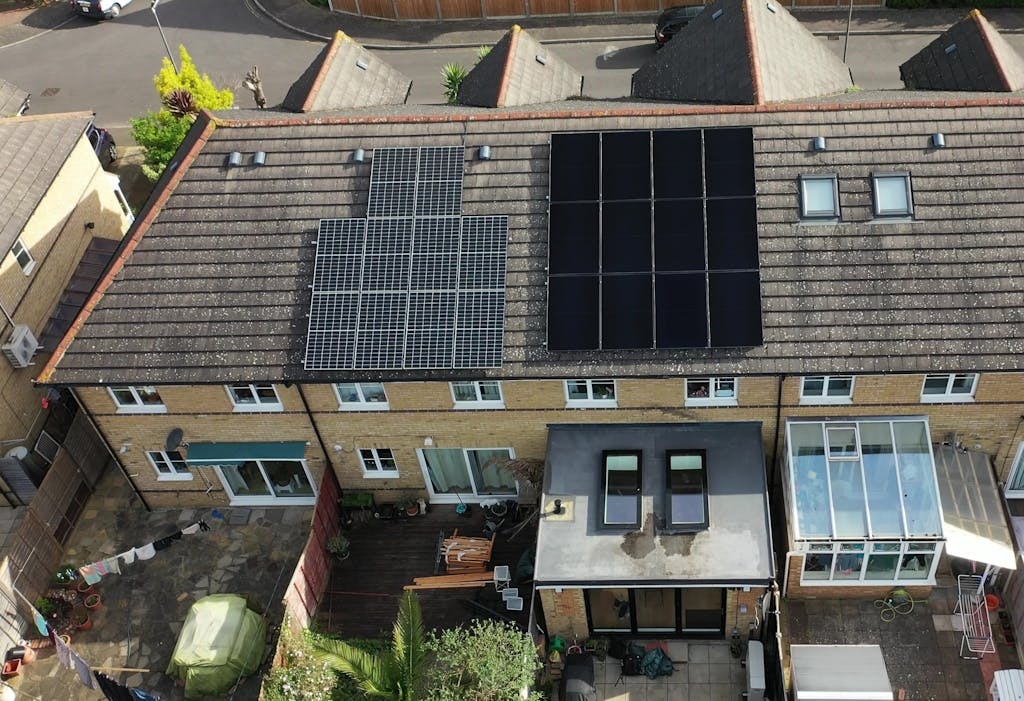 Black and blue solar panels on a brown roof, across two homes