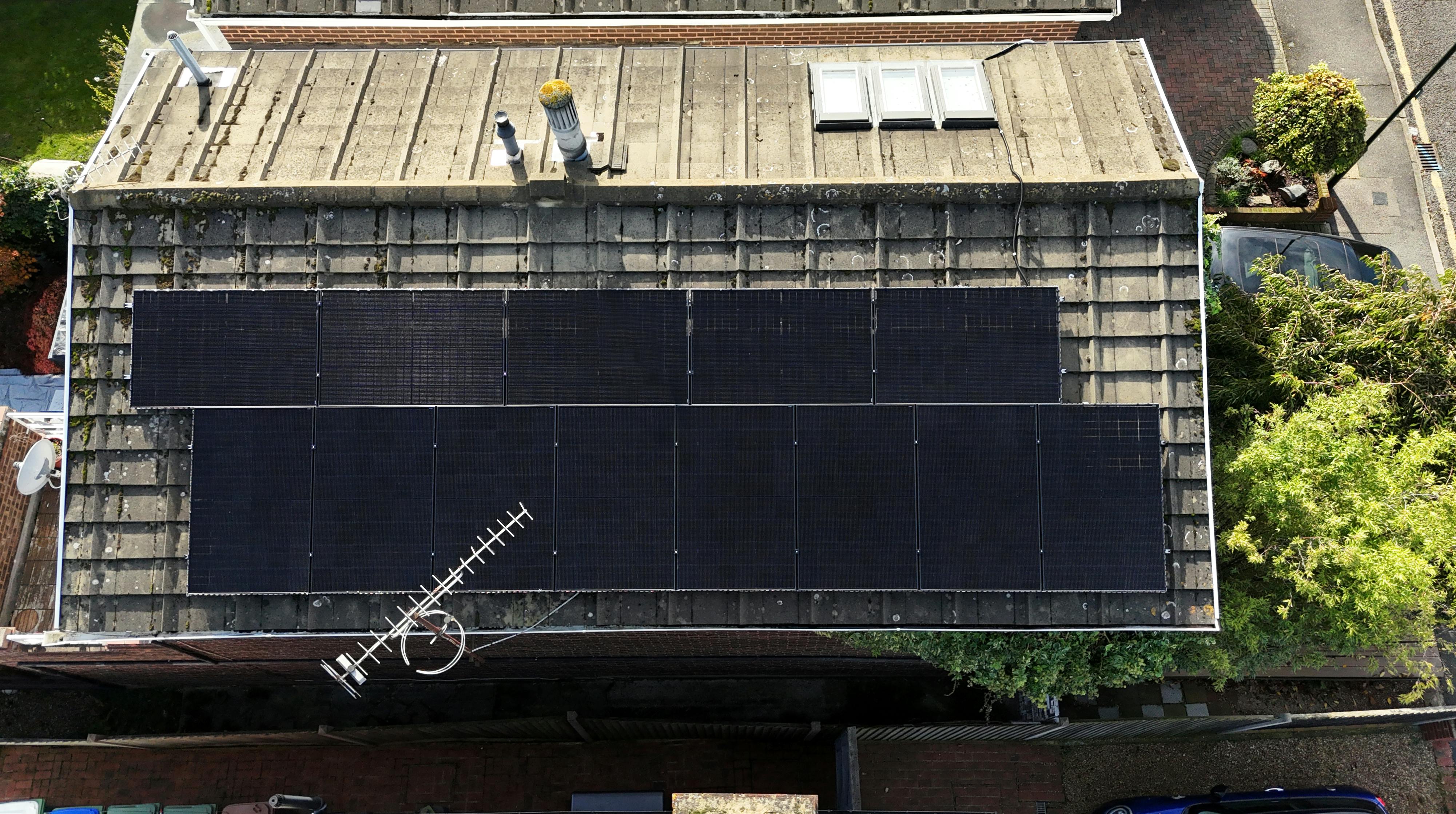 a bird's eye view of a brown roof with black solar panels on top