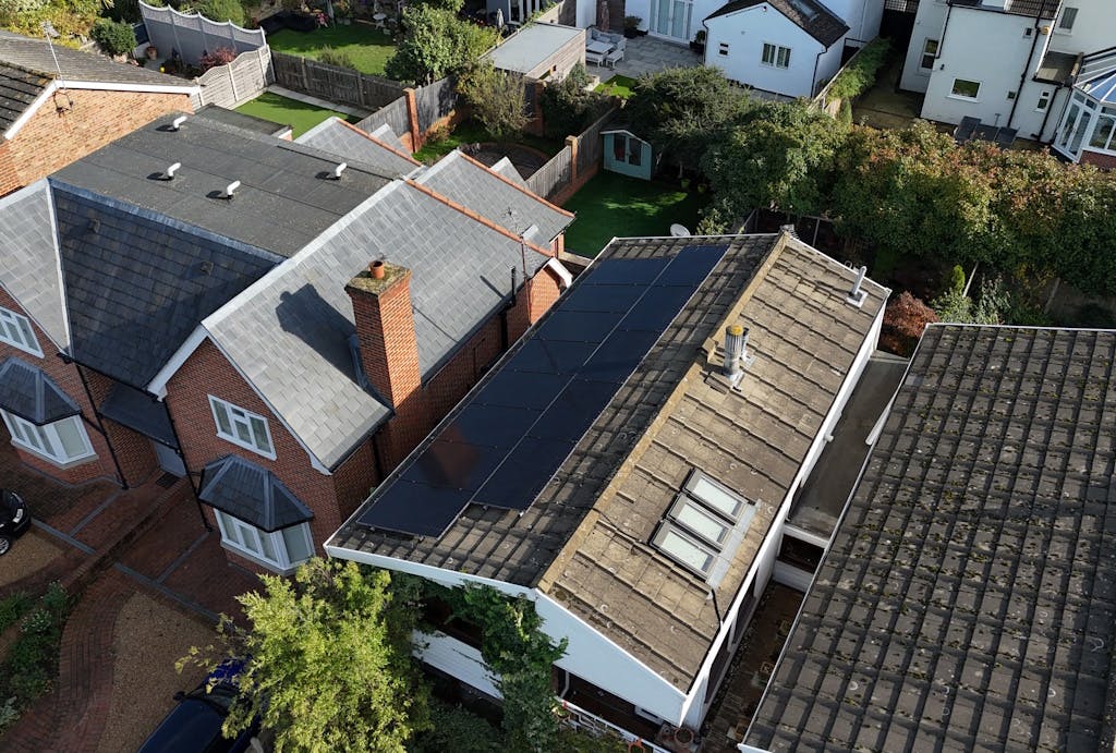 black solar panels on a brown roof next to other houses