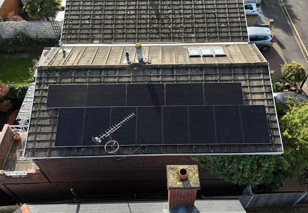 a bird's eye view of a brown roof with black solar panels on top