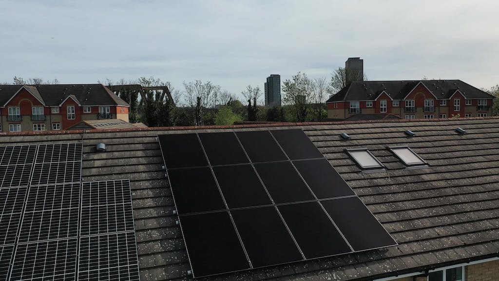 12 black solar panels on a rooftop beside an older solar PV installation, London