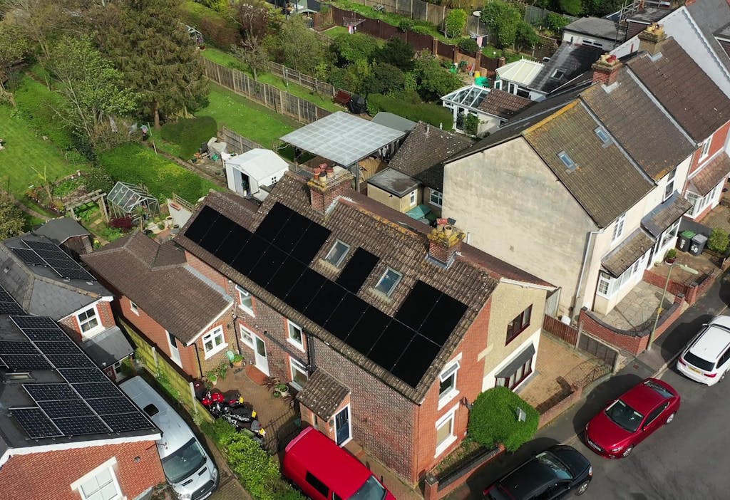 bird's-eye view of black solar panels on a brown roof of a terracotta brick house