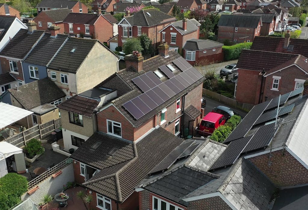 bird's-eye view of black solar panels on a dark roof of a terracotta brick house