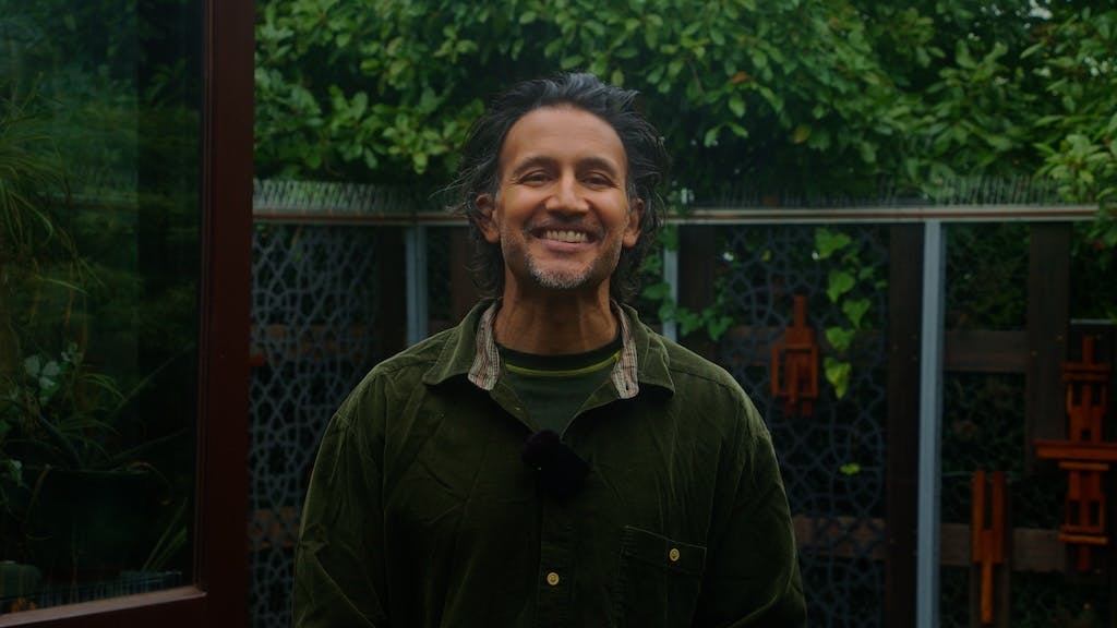 Photo of man in his garden in Sidcup, green shirt, bushes behind him