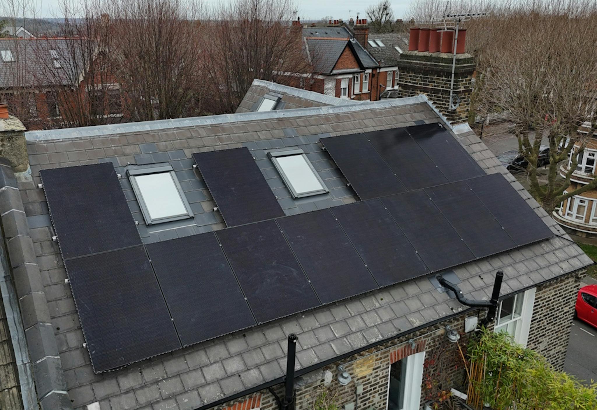 a grey roof with black solar panels and two skylights