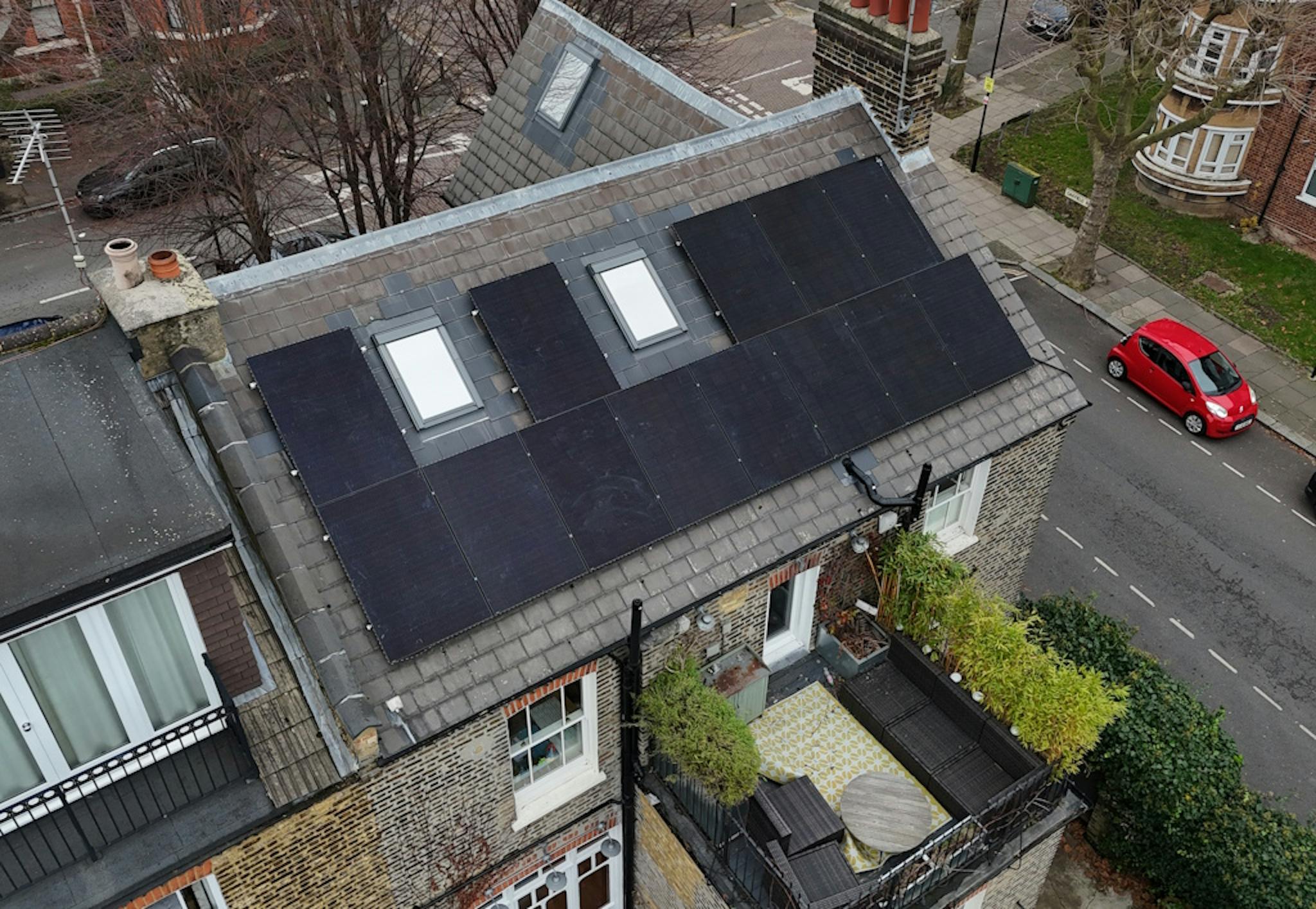 a grey roof with black solar panels and two skylights