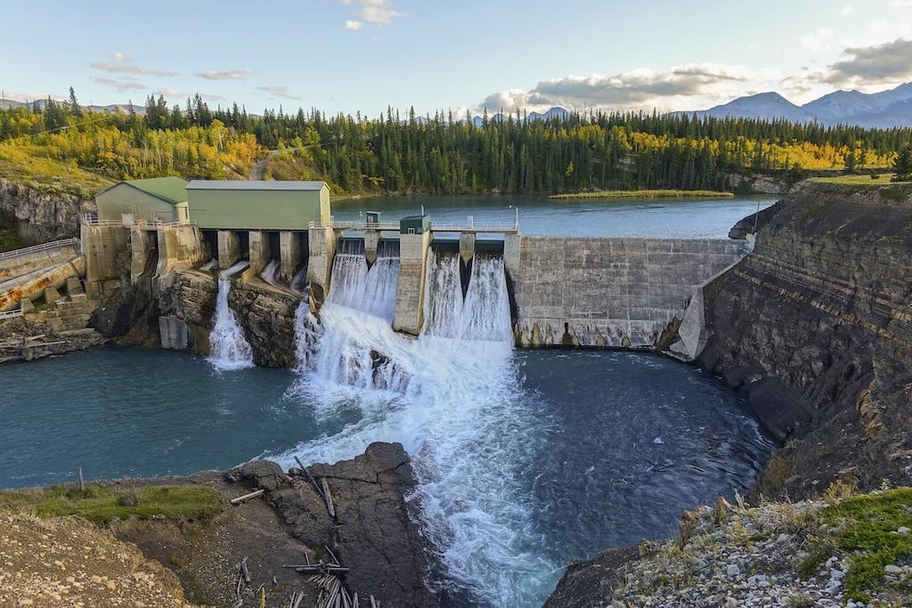 A large hydroelectric dam with trees in the background and blue sky