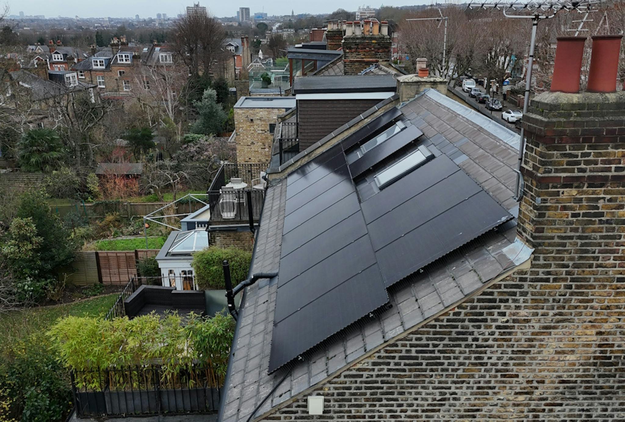 a grey roof with black solar panels and two skylights, against a backdrop of London