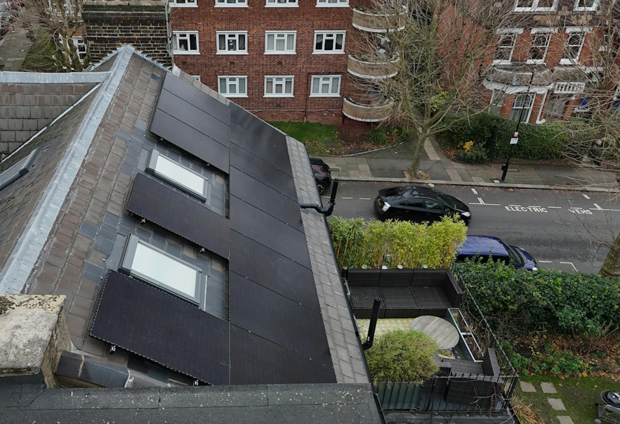 a grey roof with black solar panels and two skylights, against a backdrop of London