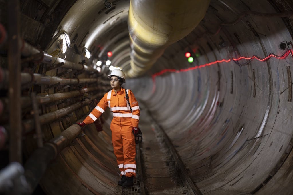 A National Grid engineer, dressed in orange hi-vis clothing, standing in an underground tunnel