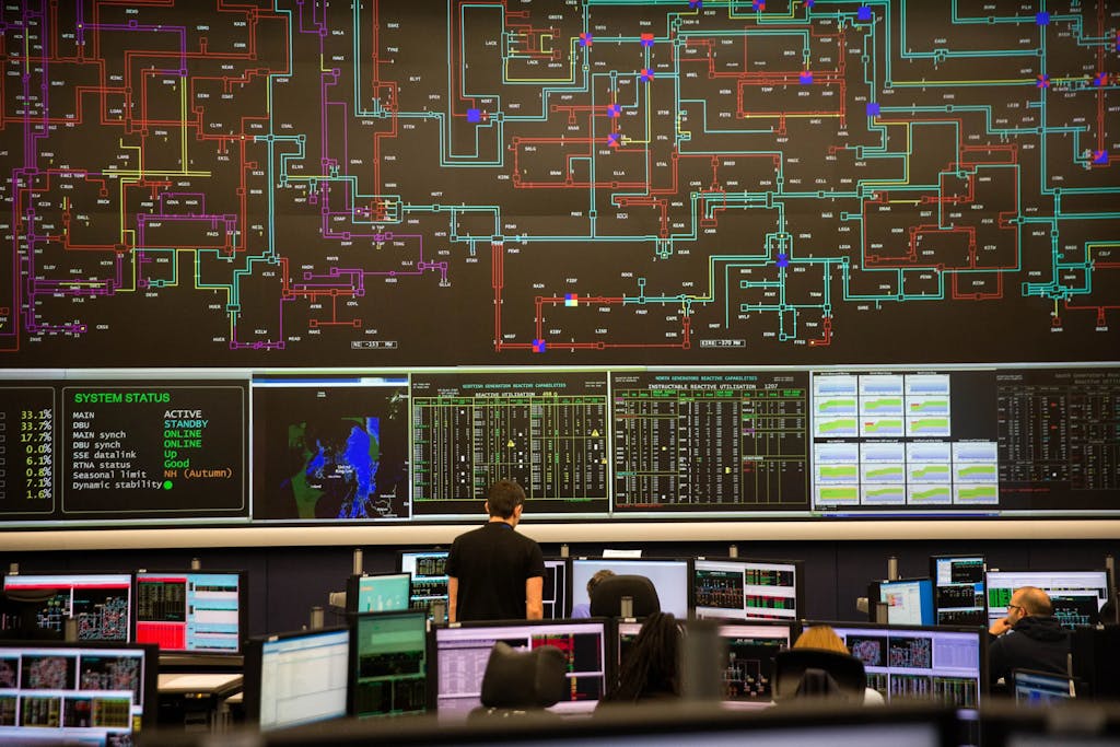 A big screen with differently coloured lines intersecting, in front of many smaller screen