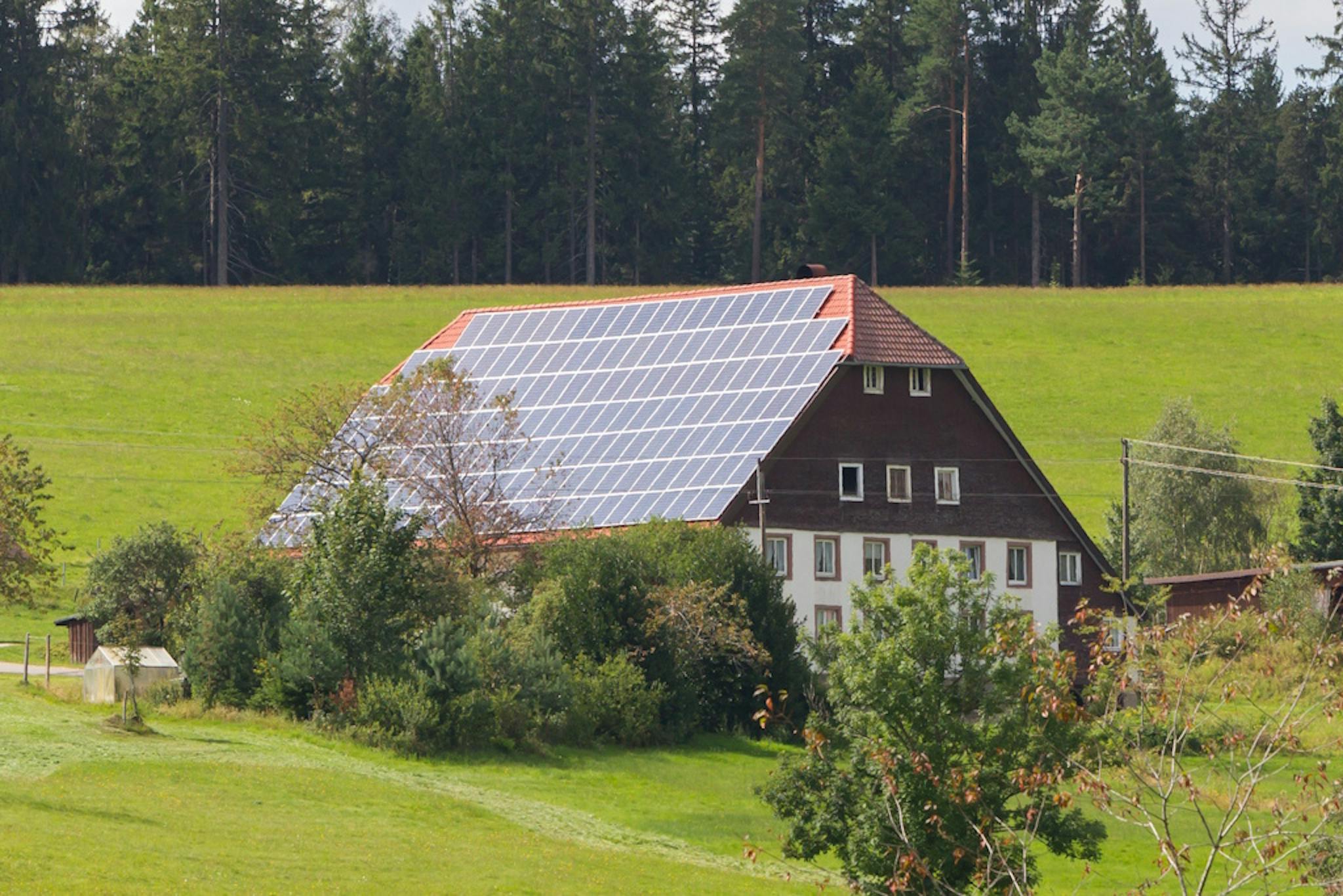 A large house in the Black Forest with black solar panels covering the roof