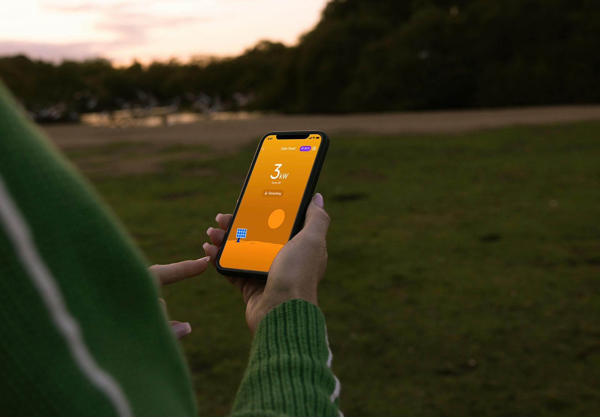 person holding a phone showing the Hive app on its screen, against a park background at twilight