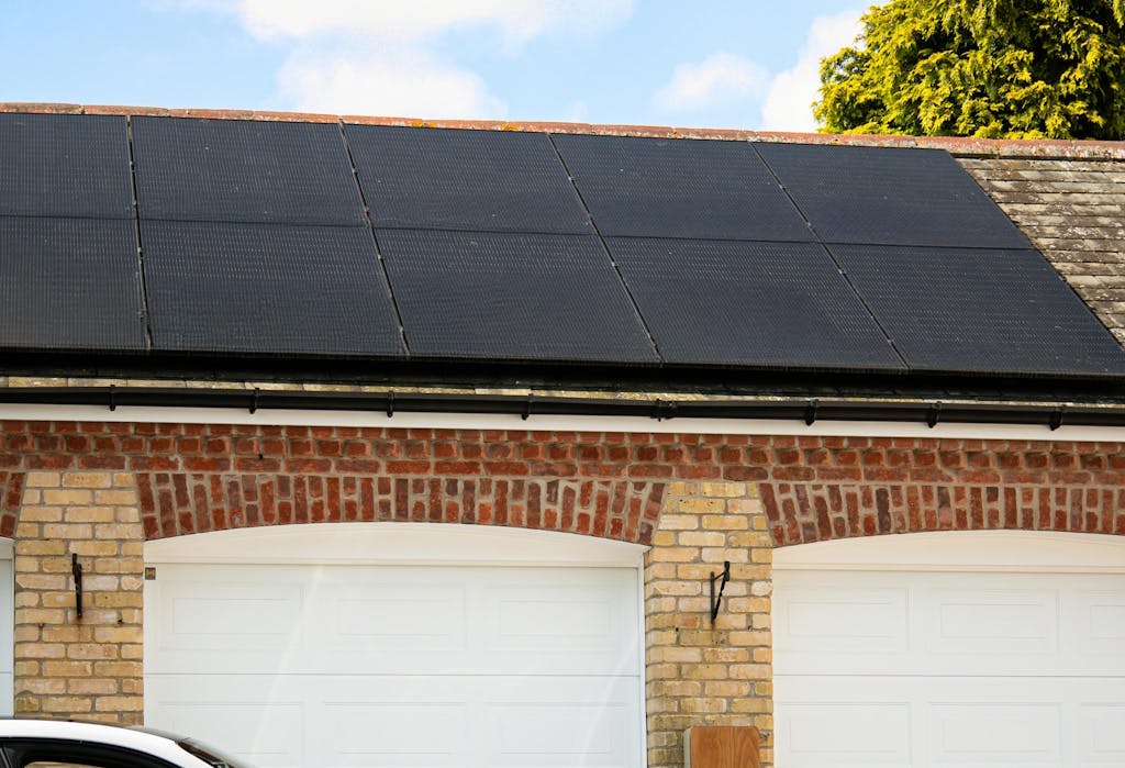 Black solar panels on a garage roof, with blue sky above