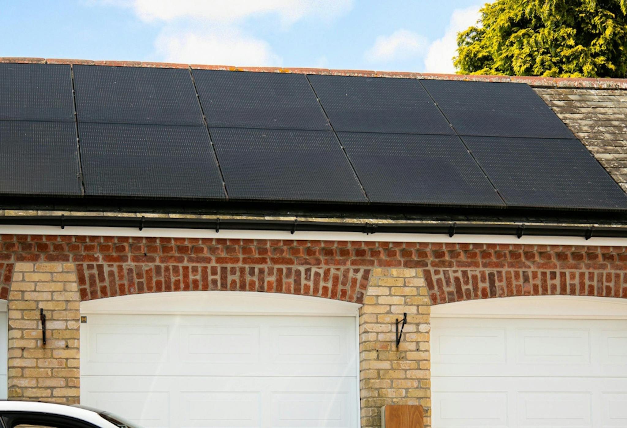 Black solar panels on a garage roof, with blue sky above