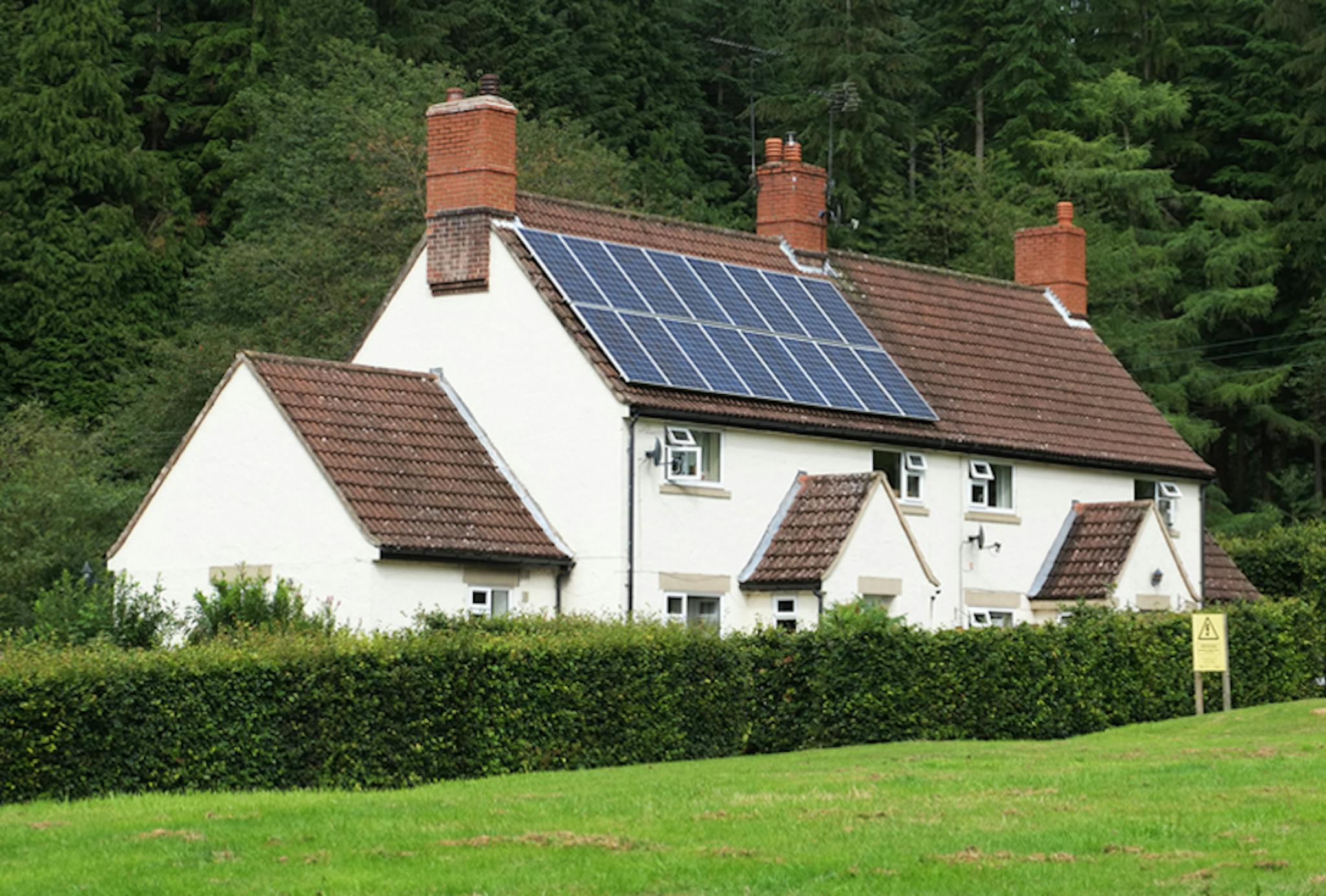 solar panels on a brown roof, by a green space