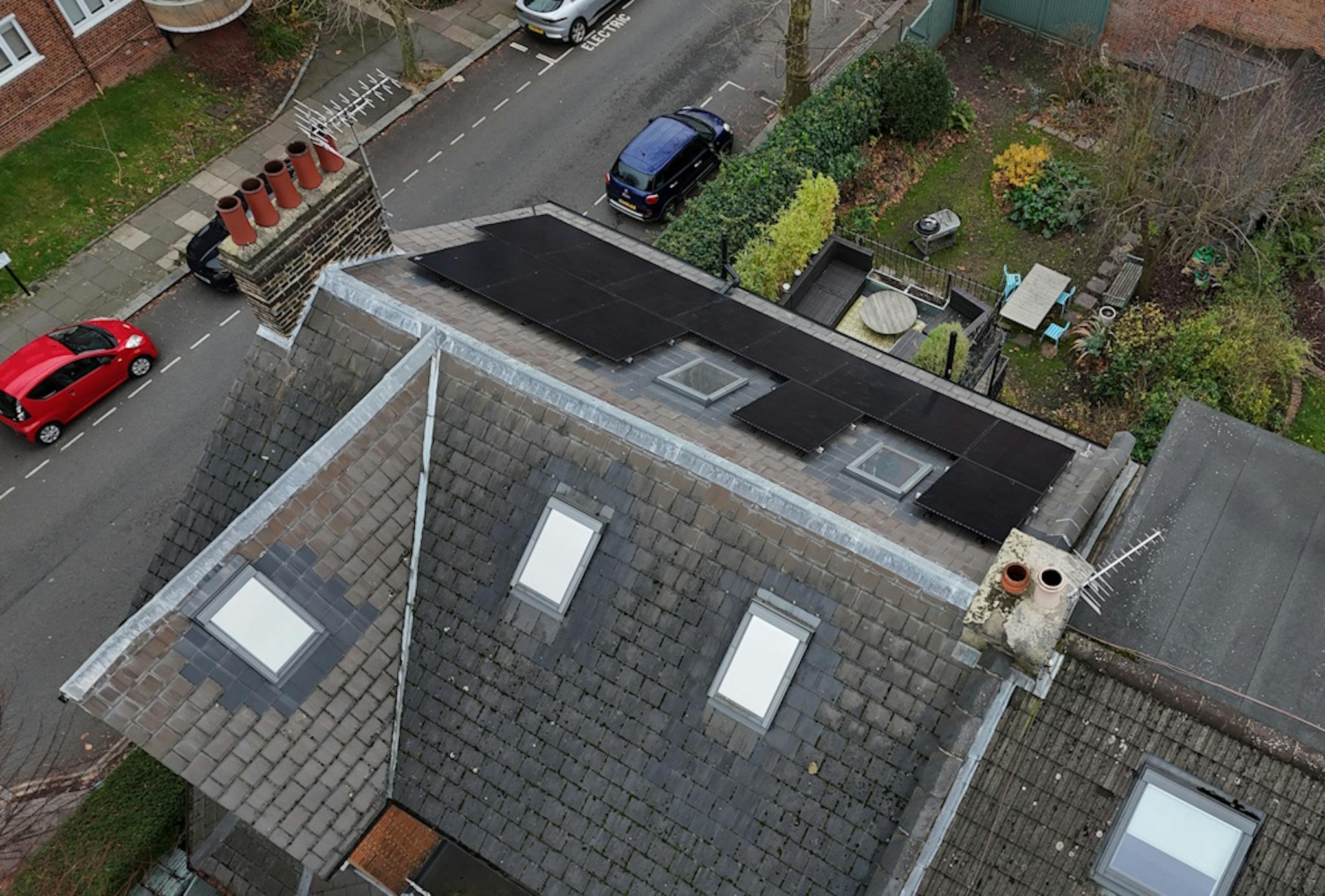 a grey roof with black solar panels and skylights, next to a grey road