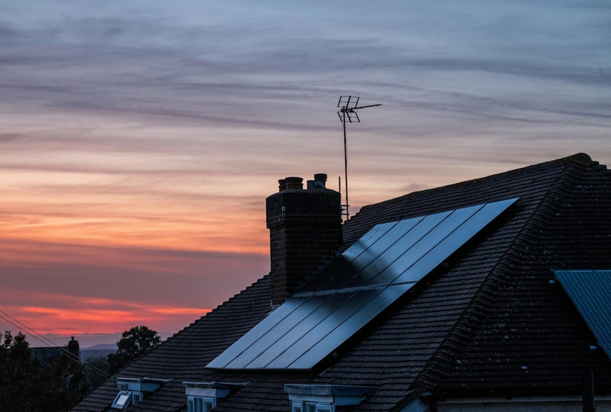 black solar panels on a roof at sunset
