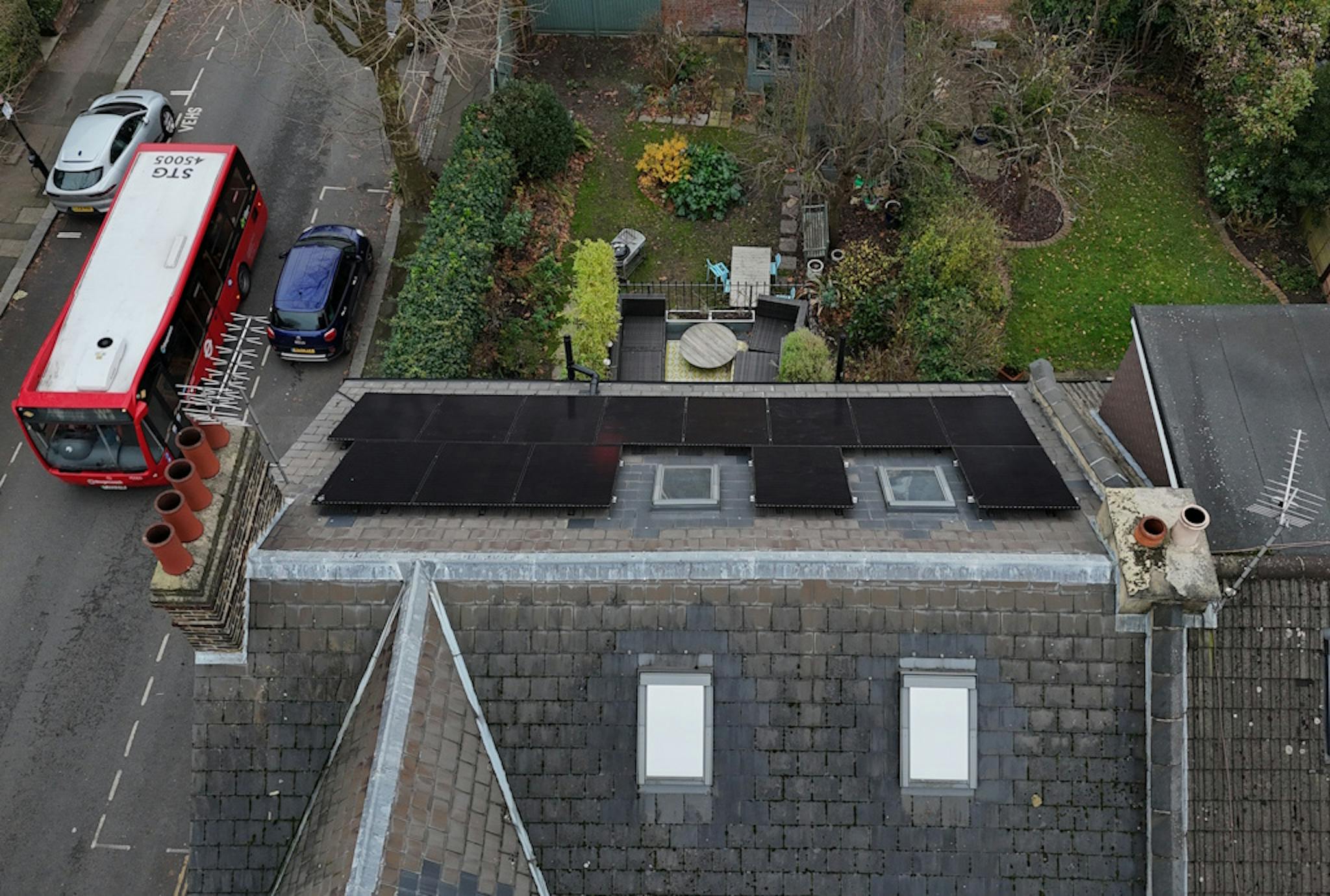 a grey roof with black solar panels and skylights, next to a grey road