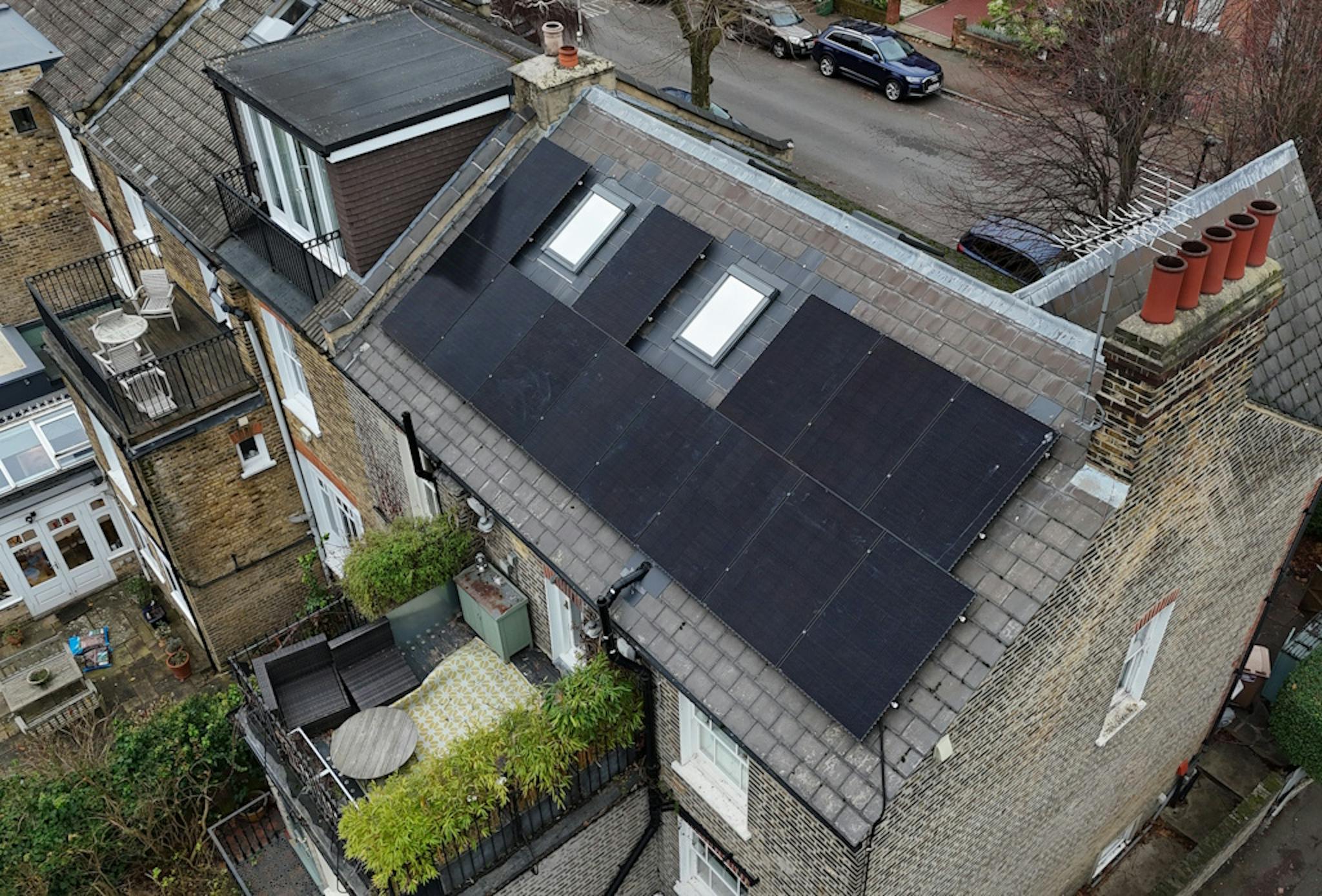 a grey roof with black solar panels and skylights, next to a road