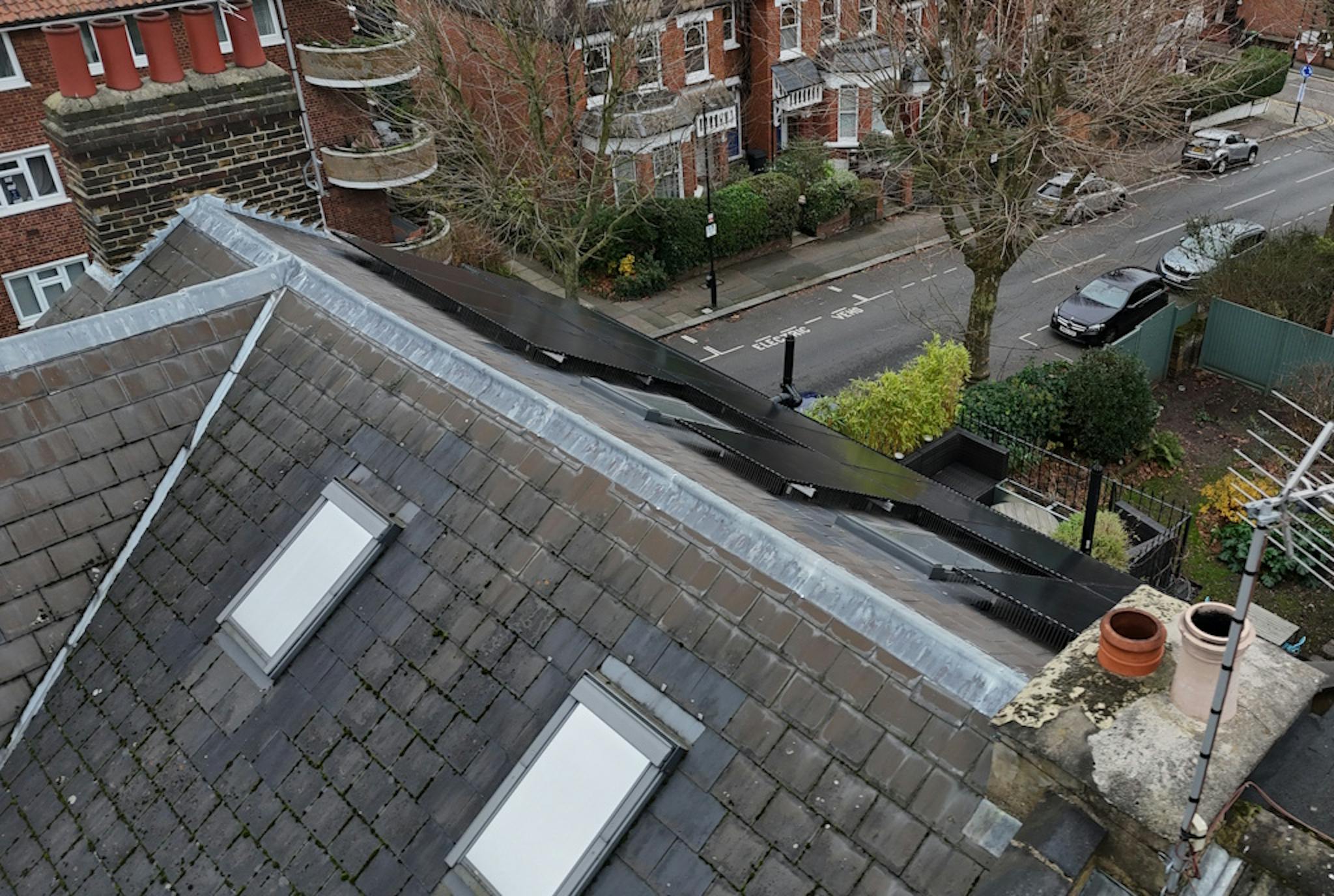 a grey roof with black solar panels and skylights, next to a road