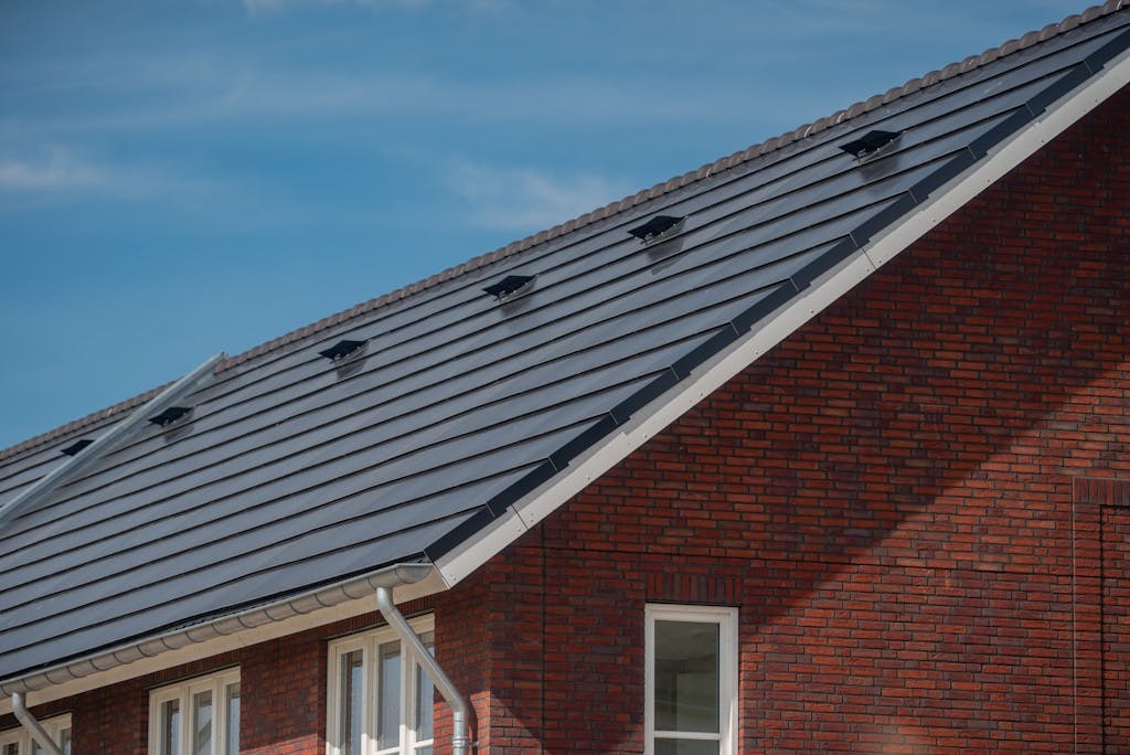 solar tiles on the roof of a brick house, under a blue sky