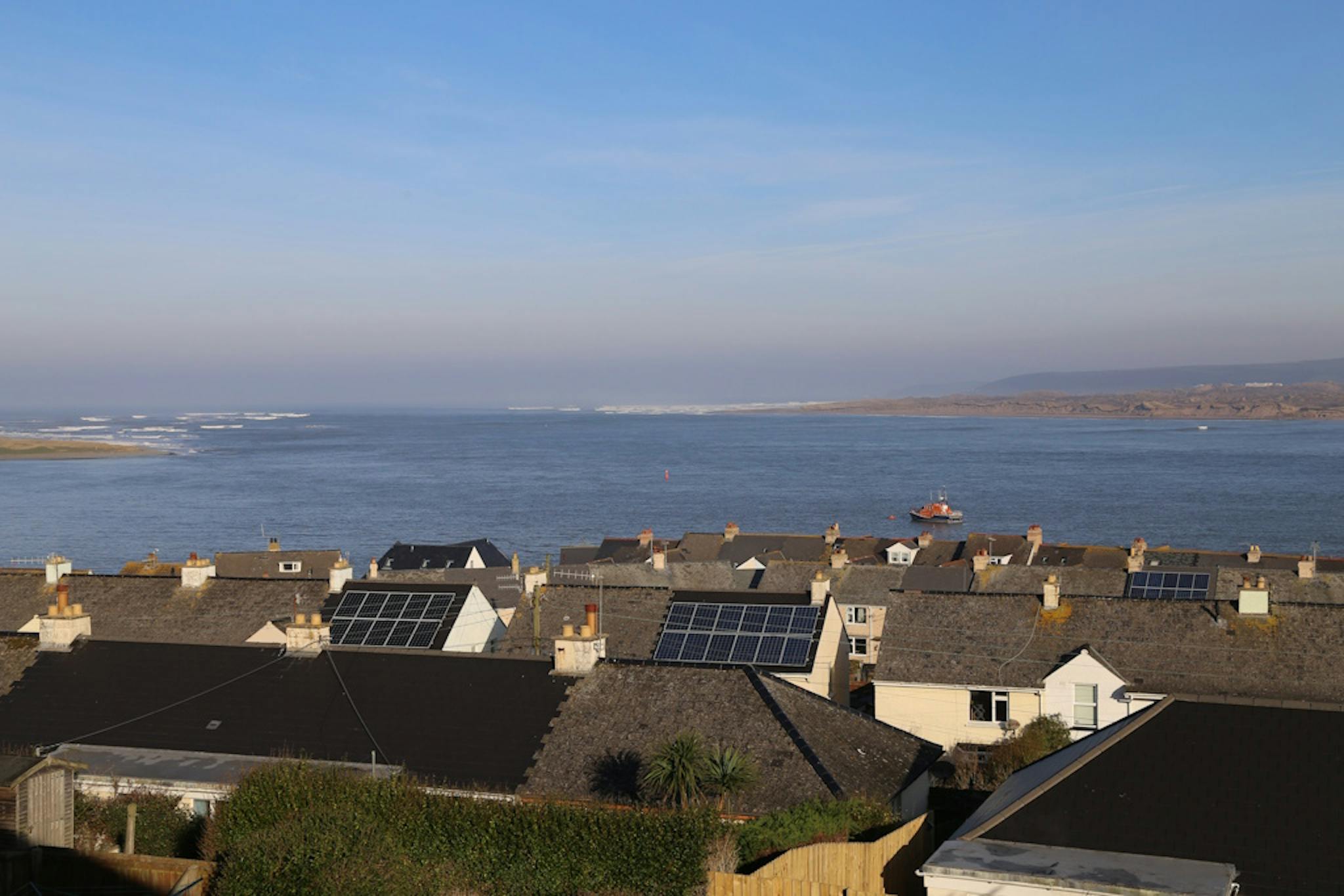 a view of rooftops with solar panels and the coast in Appledore, Devon
