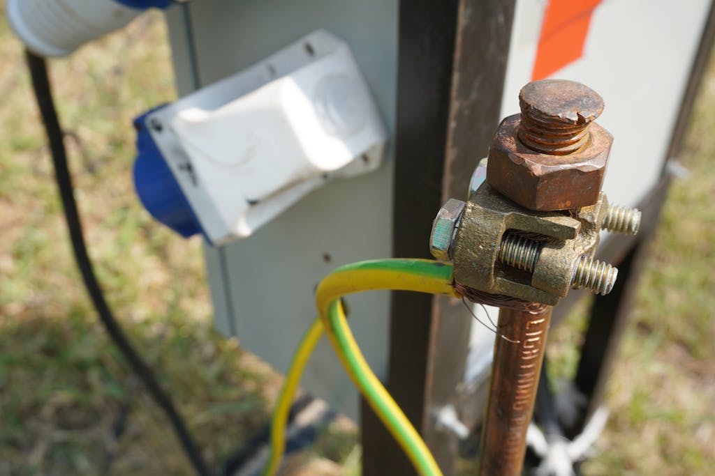 a copper earth rod in the ground, with green-and-yellow wires coming out of it