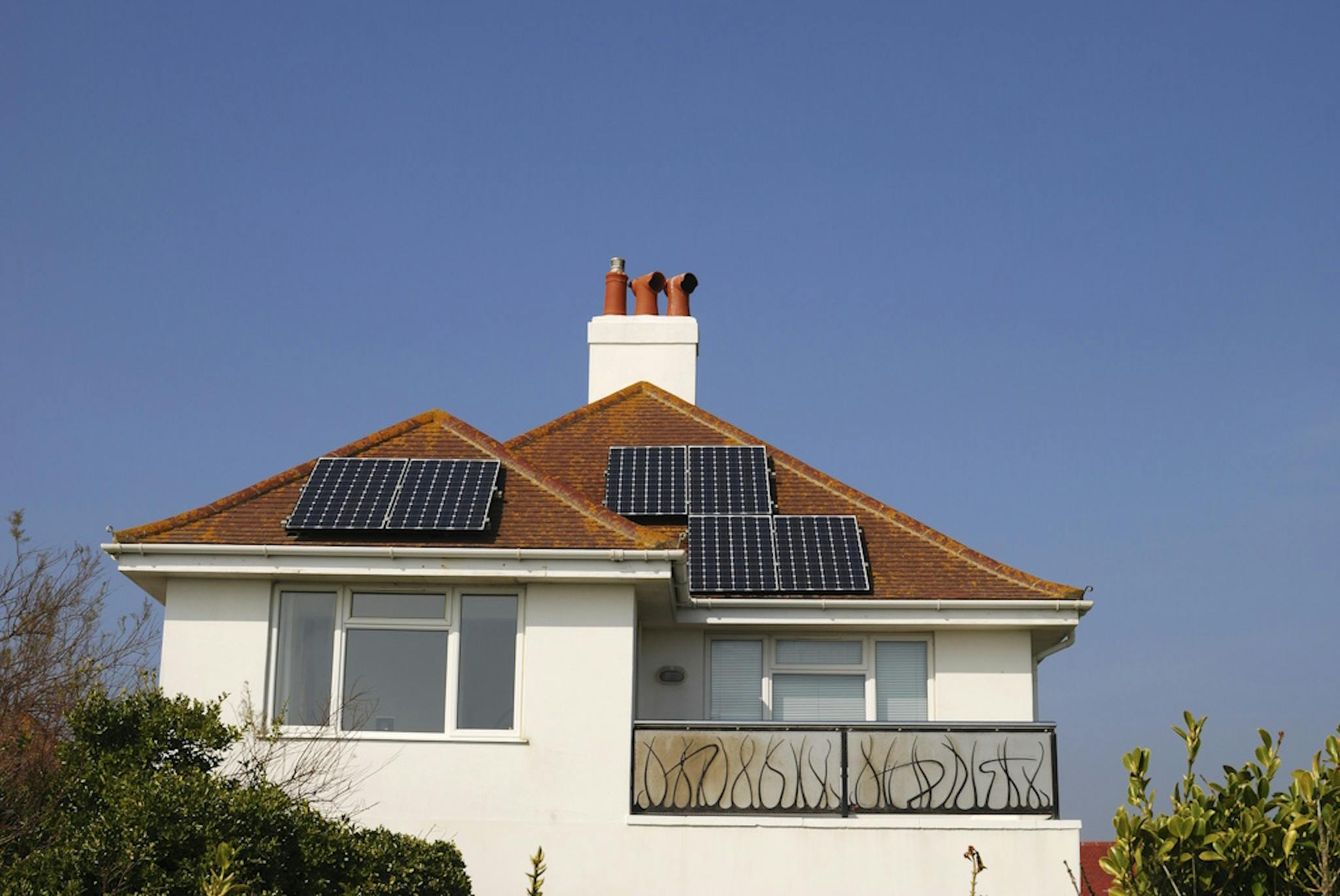 black solar panels on a terracotta roof, under a blue sky