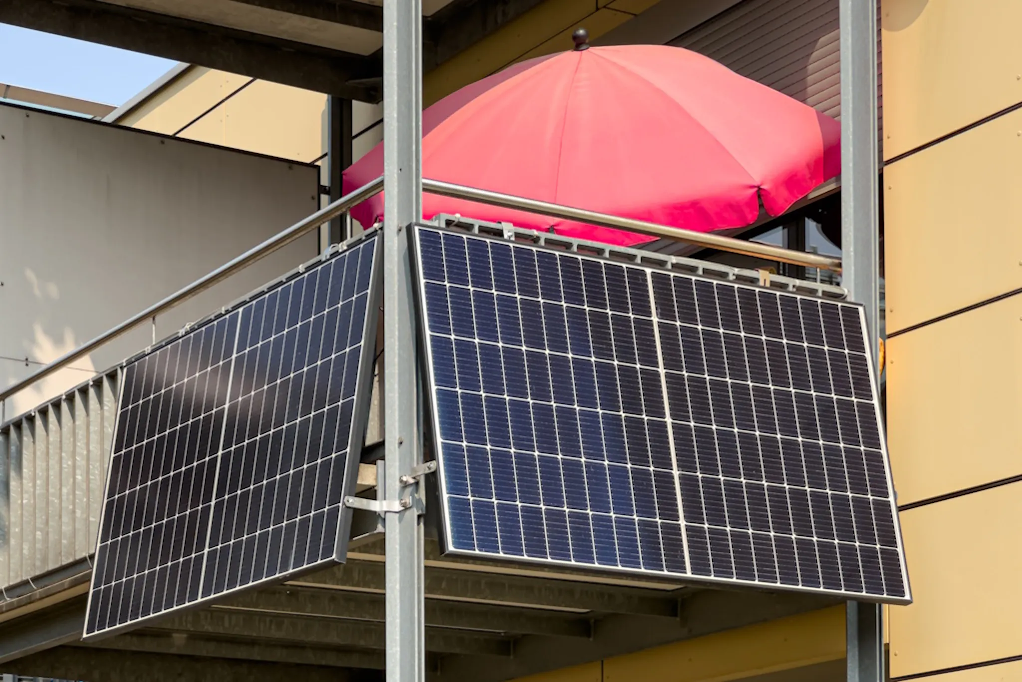 black solar panels on a balcony, with a red umbrella