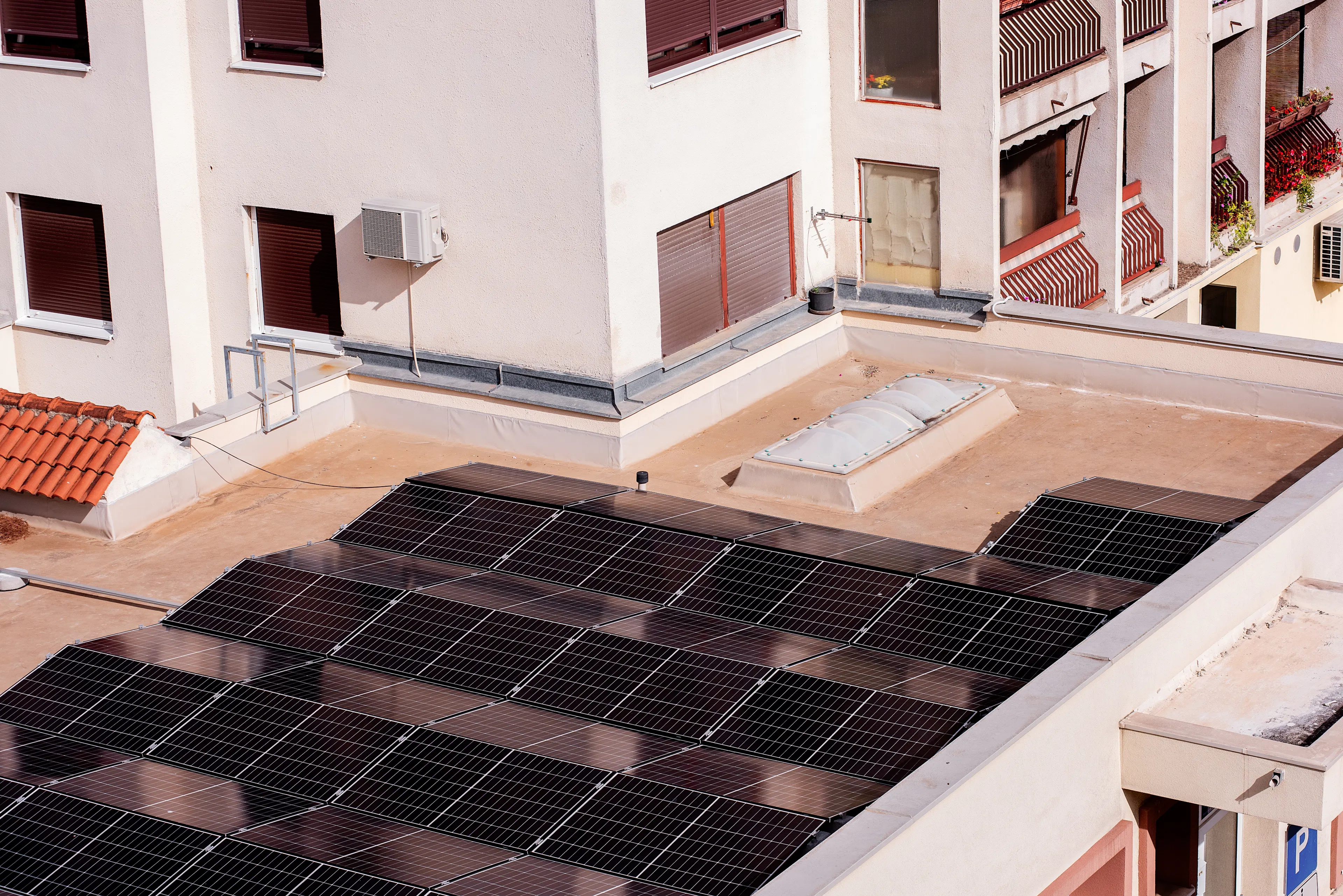 black solar panels on the flat roof of a block of flats