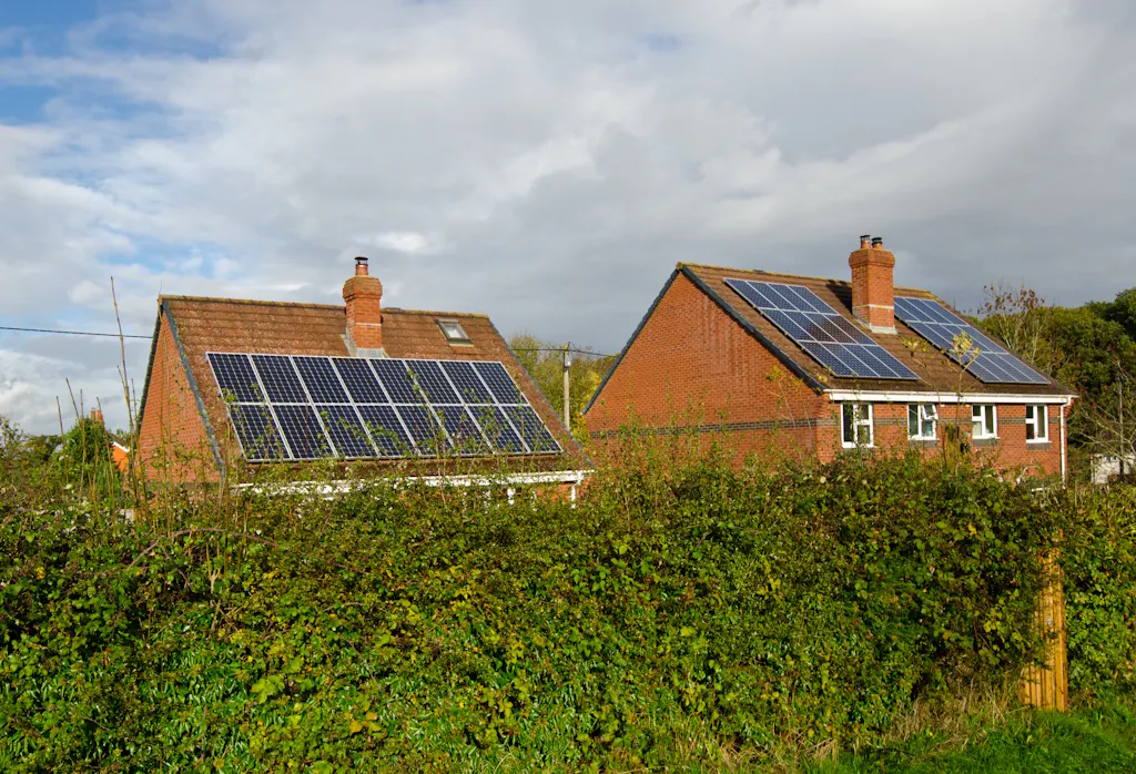 solar panels on two brick houses, under a cloudy sky