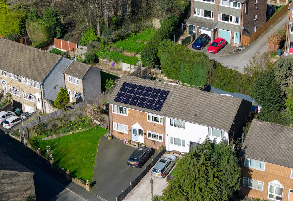 solar panels on a house, next to other houses with gardens