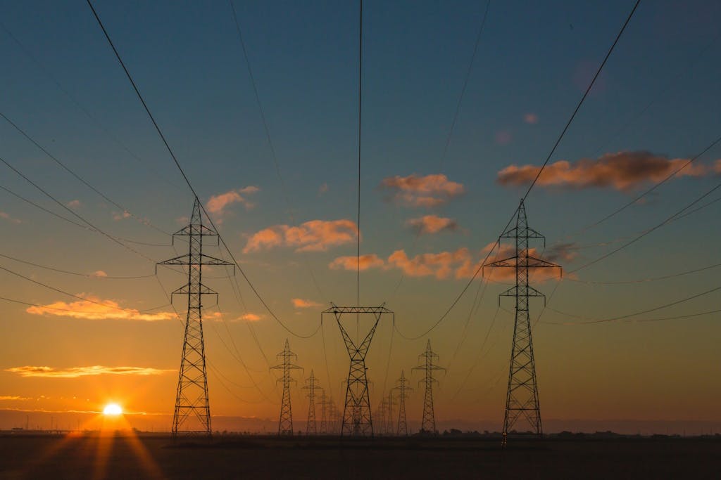 a landscape with a series of electricity pylons set against a sunset