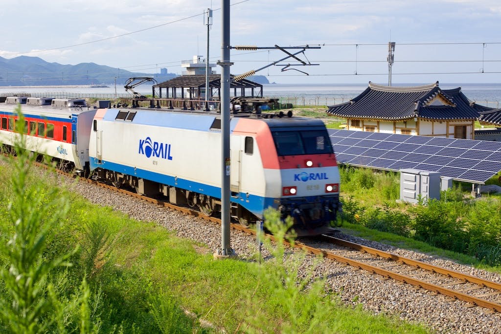 A train going past solar panels in the countryside, South Korea