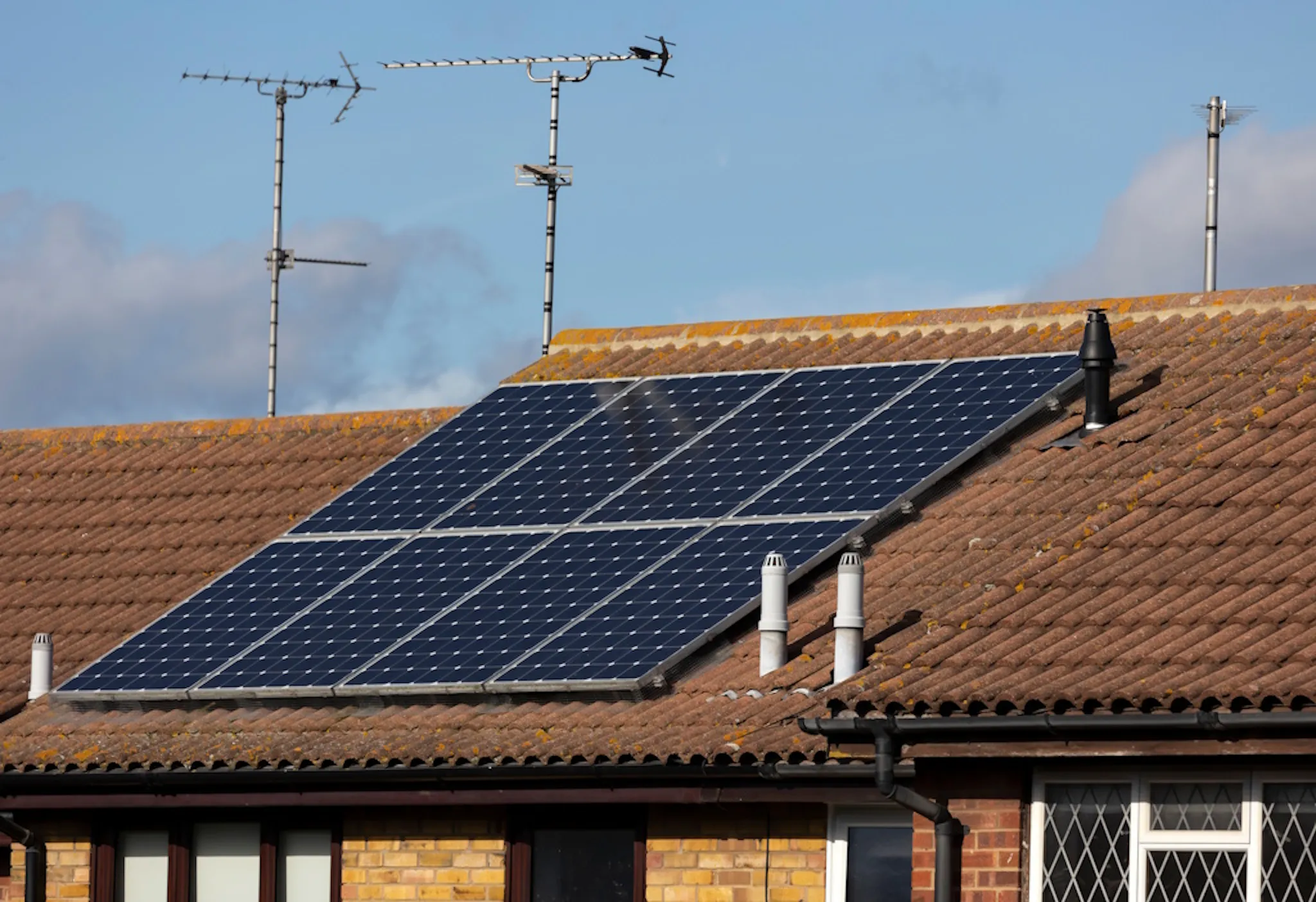 terracotta roof under a blue sky, with black solar panels
