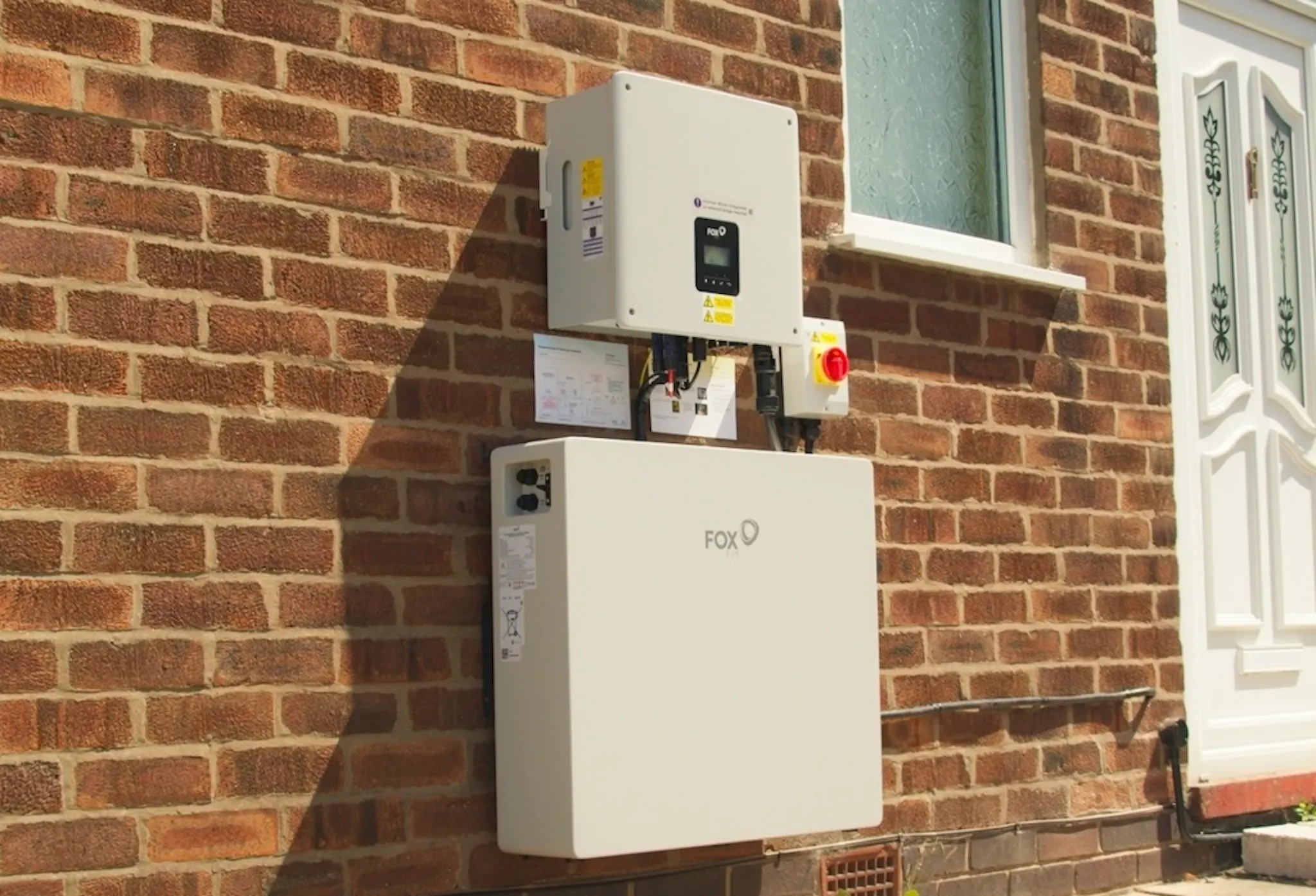 A battery and inverter on a brick wall, near a white door