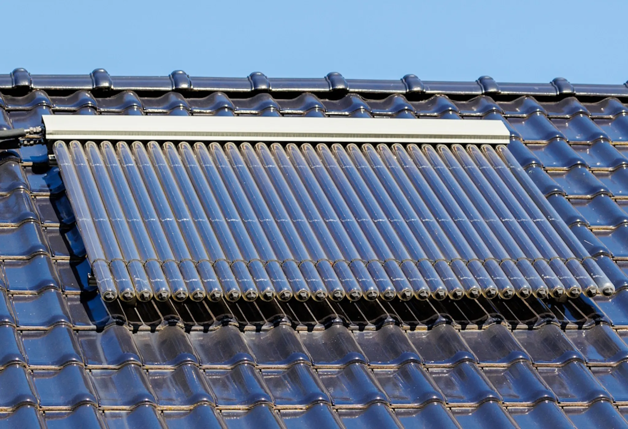 solar thermal panels on a black roof, under a blue sky