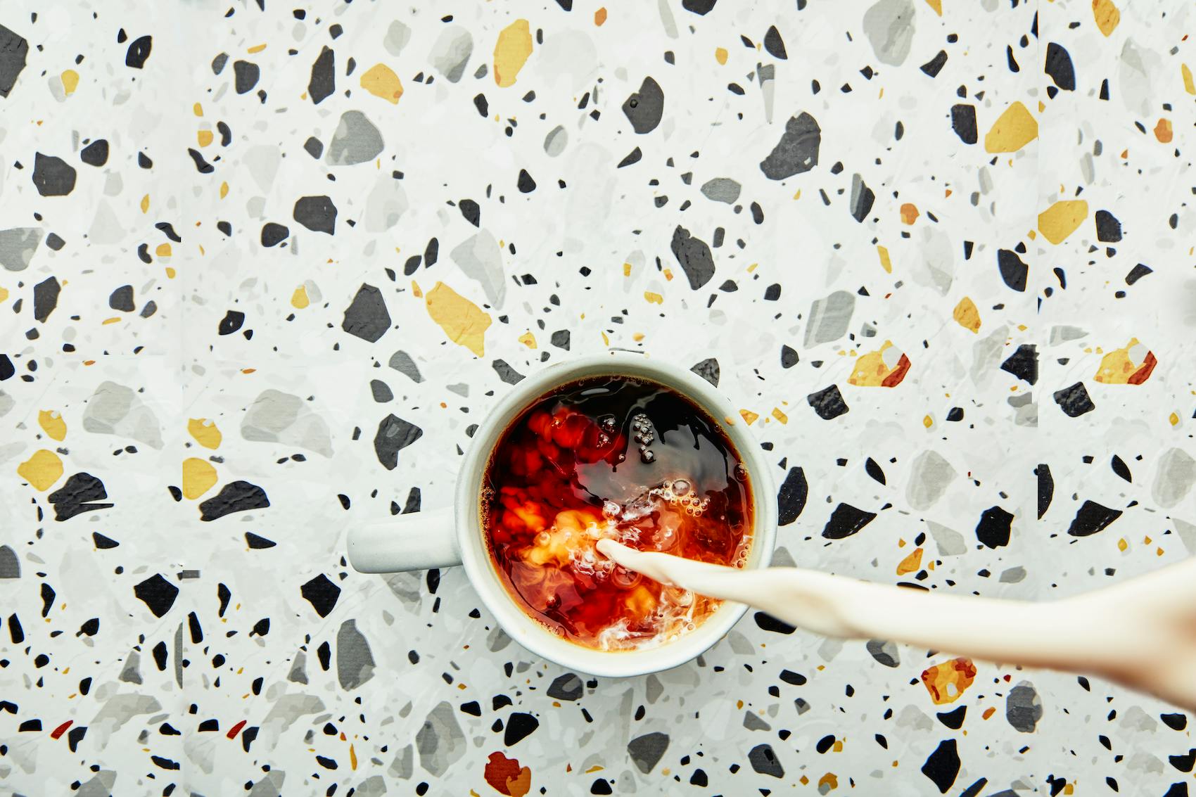 Pouring cream into a cup of coffee