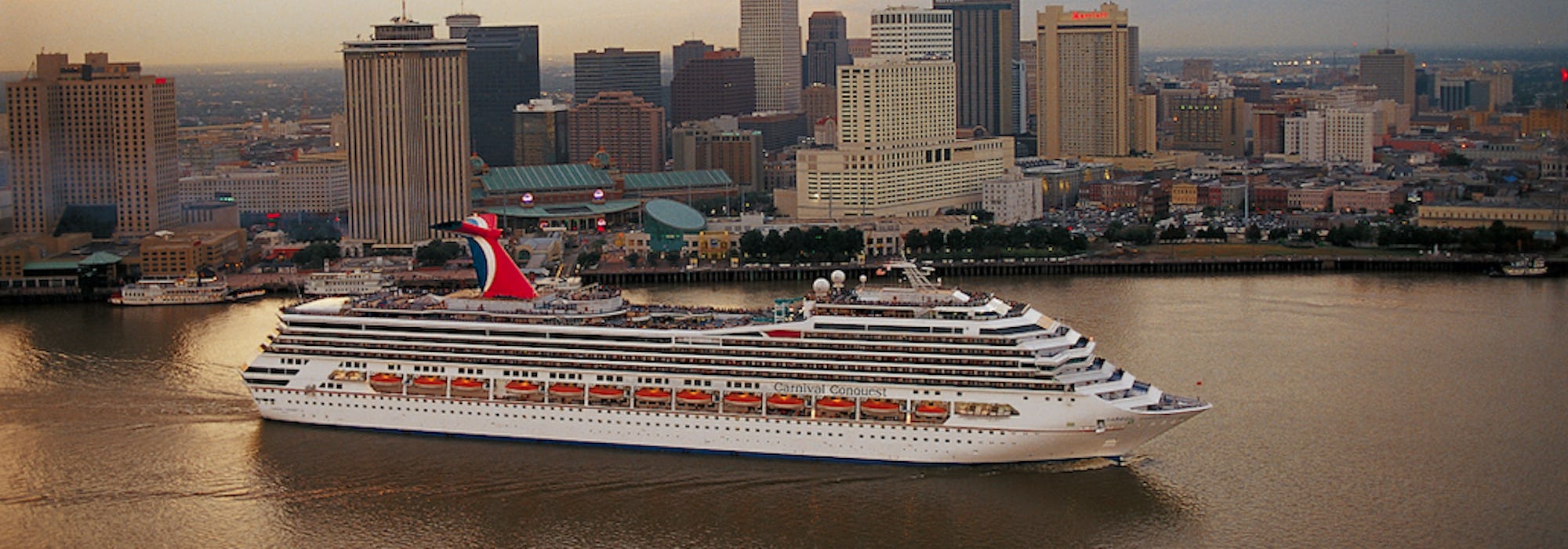Fartyget Carnival Conquest kryssar fram framför flera skyskrapor.