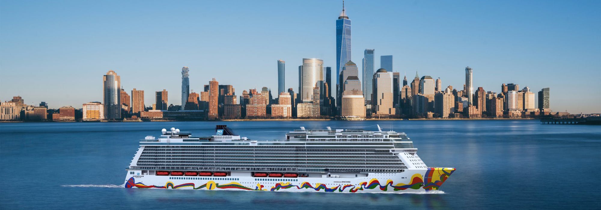 Norwegian Encore från sidan med Manhattans skyskrapor i New York i bakgrunden.