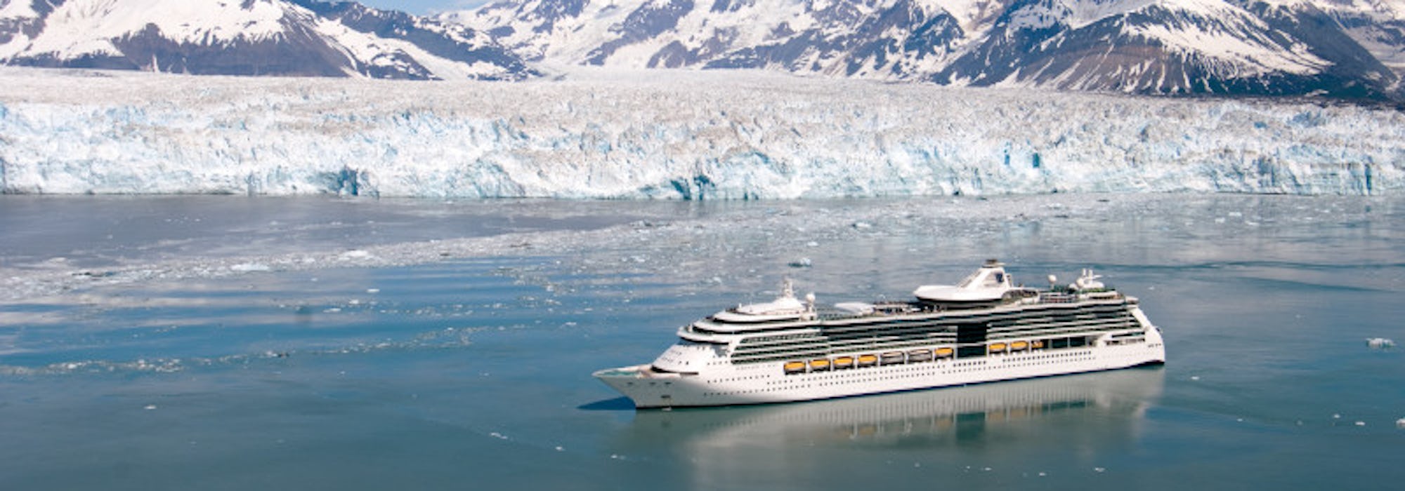 Bild från ovan på Serenade of the Seas som kryssar fram vid snötäckta berg och isberg i Alaska.