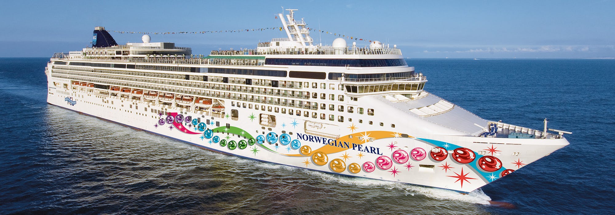 Bild på Norwegian Pearl tagen från sidan medan fartyget kryssar sig fram.