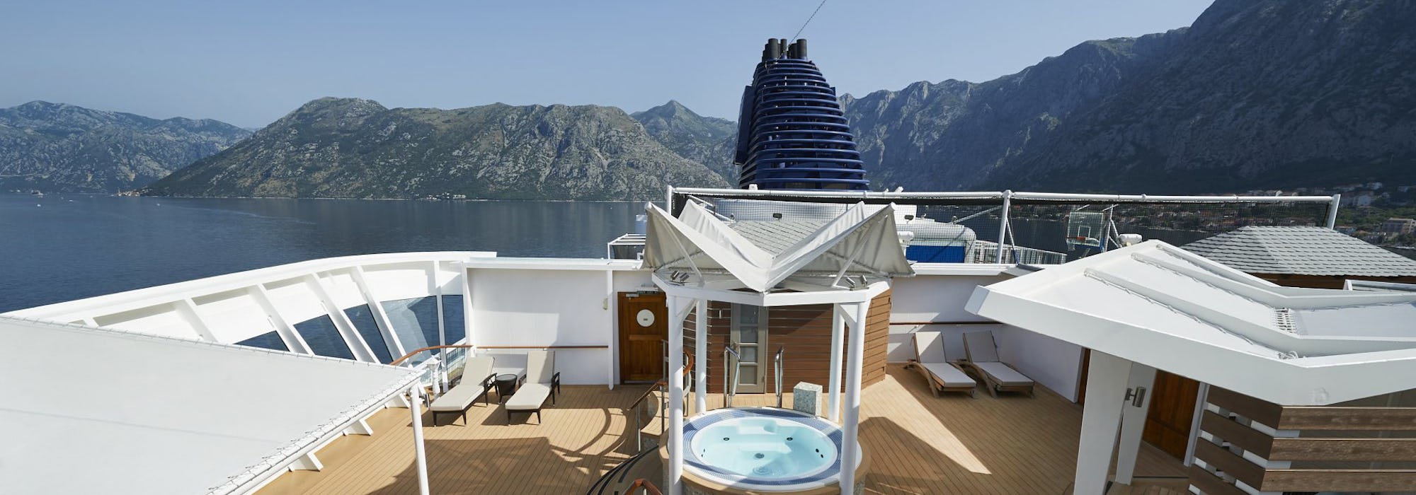 Bild på Norwegian Star's däck med höga berg i bakgrunden.