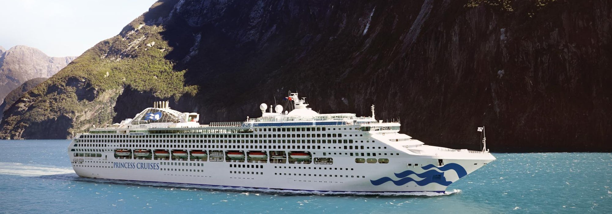 Bild från sidan på fartyget Sea Princess, i bakgrunden syns ett högt berg.