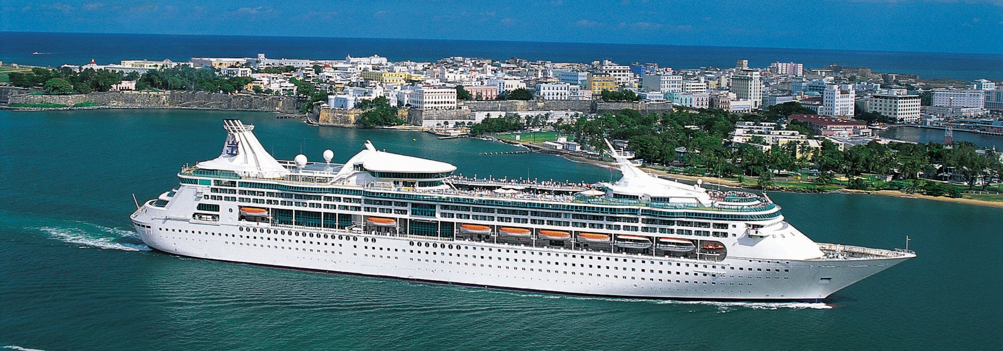 Fartyget Enchantment of the Seas kryssar förbi en mindre ö.